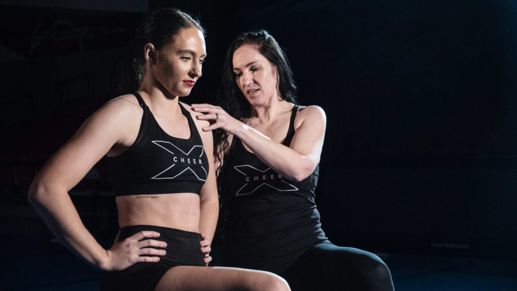 cheerleader being instructed in spine position with hip flexor stretch